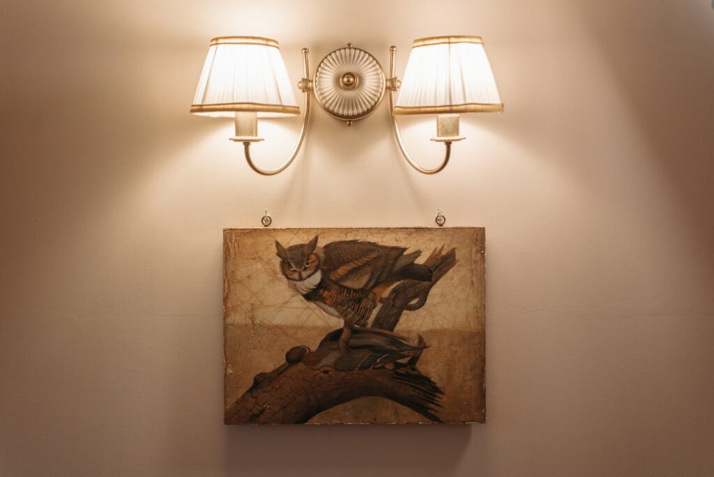 Vintage painting with dual sconces on a neutral wall for elegant decor inspiration.
